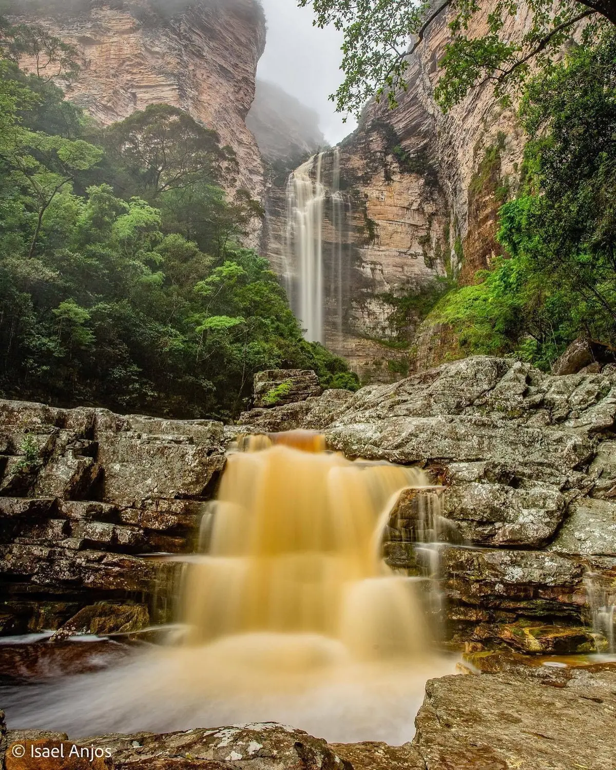 Cachoeira alta caindo entre paredões de rocha em camadas