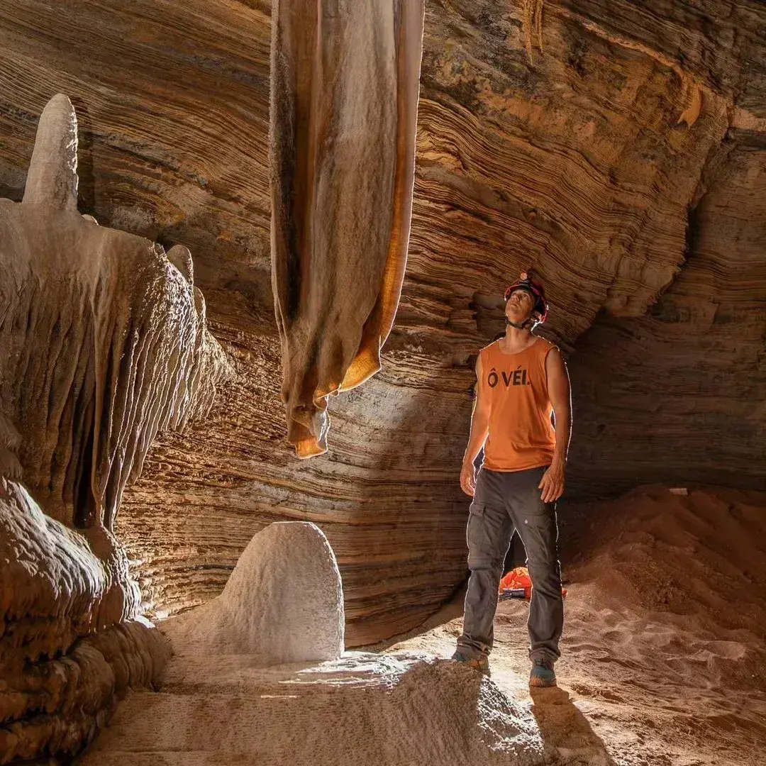 Pessoa de capacete entre formações de calcário dentro de uma gruta