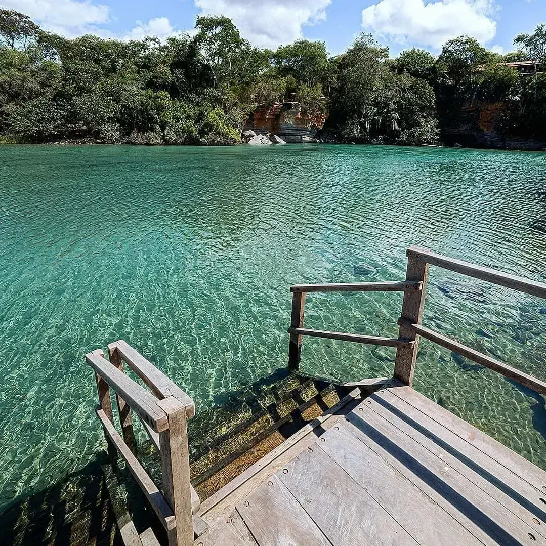 Deck de madeira com escada descendo até a água turquesa do Rio Pratinha