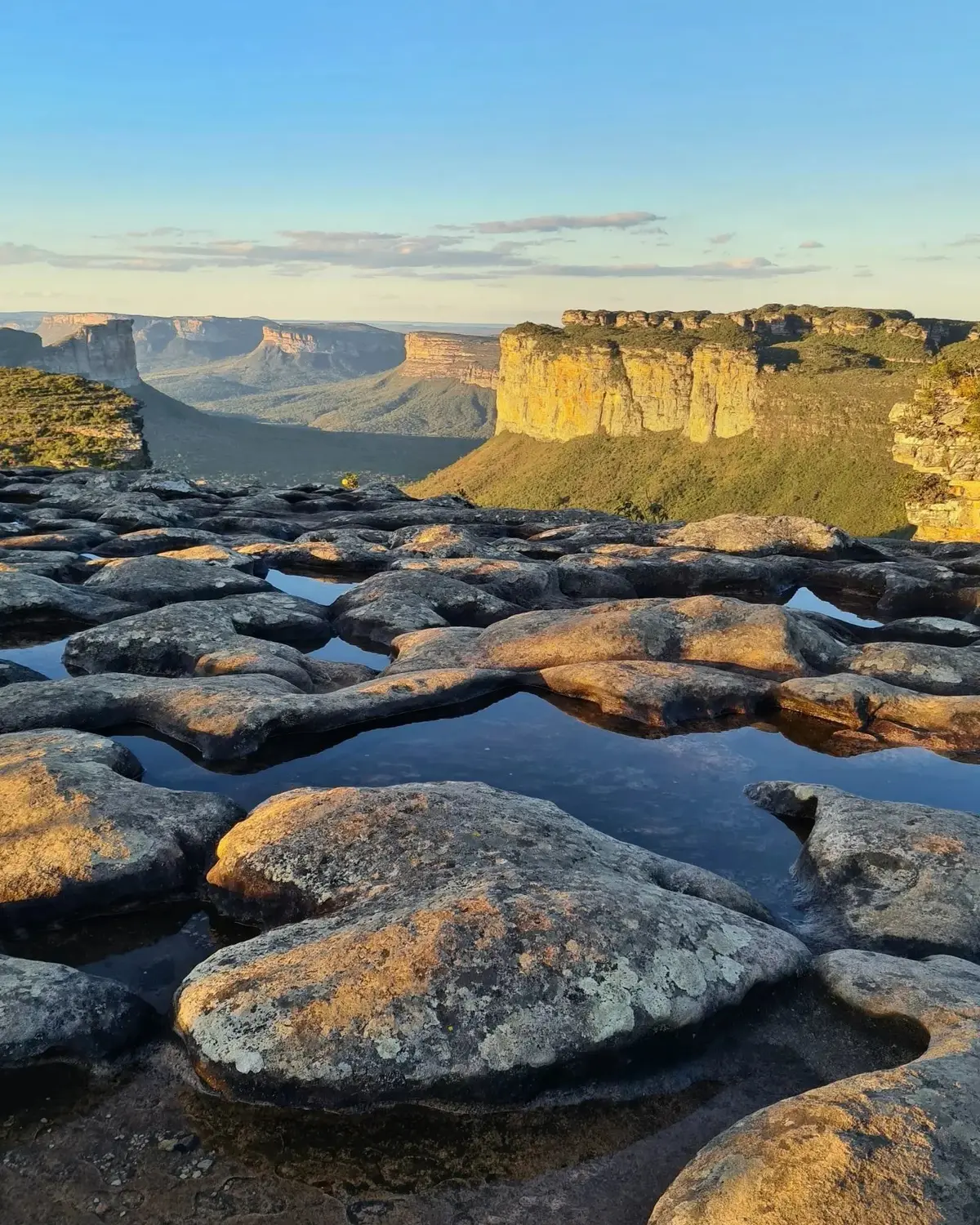 Poças de água no lajedo do topo do Pai Inácio e morros de topo plano iluminados pelo pôr do sol