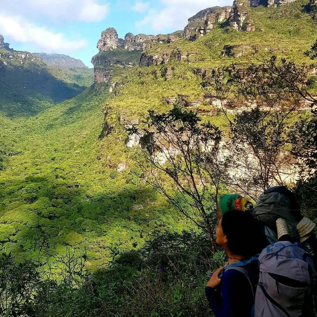 Caminhante de costas olhando o Vale do Pati cercado de paredões