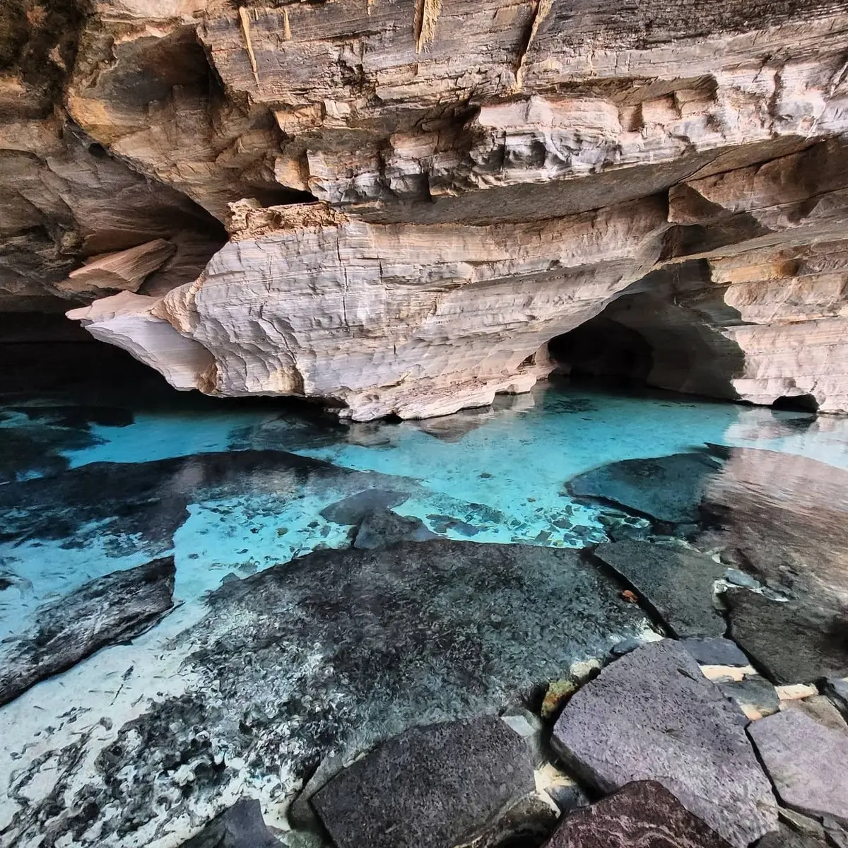 Gruta da Pratinha: água azul-turquesa transparente sob um paredão de rocha clara e escura