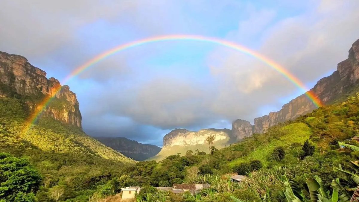 Rainbow over local residents' houses and green cliffs in Vale do Pati